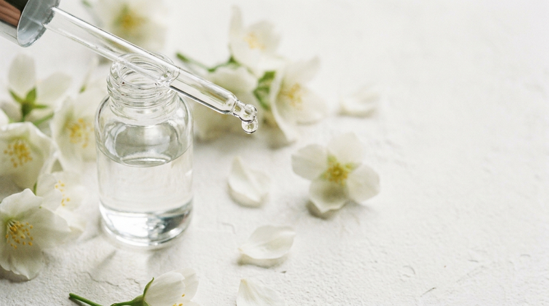 Jasminblüten neben klarem Fläschchen mit Pipette — Symbolbild Hedion
