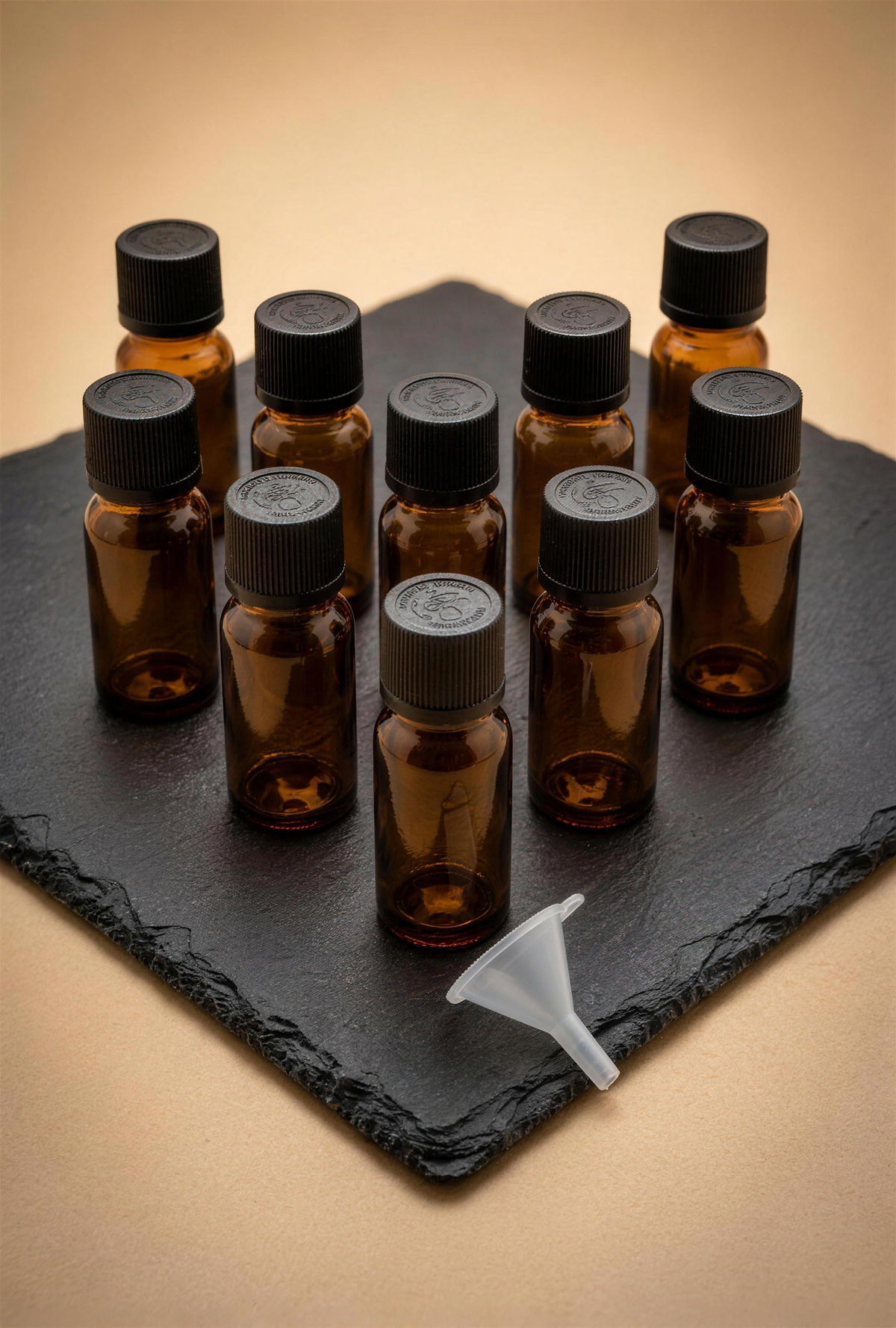 10 Apotheker-Fläschchen 20 ml Braunglas mit kindersicherem Drück-Dreh-Verschluss und Mini-Trichter auf rauer Schieferplatte — Duftatelier